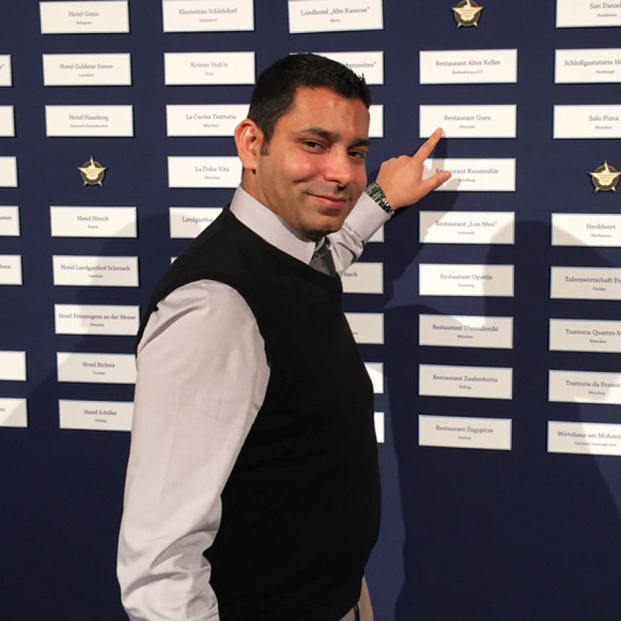 Inhaber des GURU Restaurants zeigt Auszeichnungen an der Wand