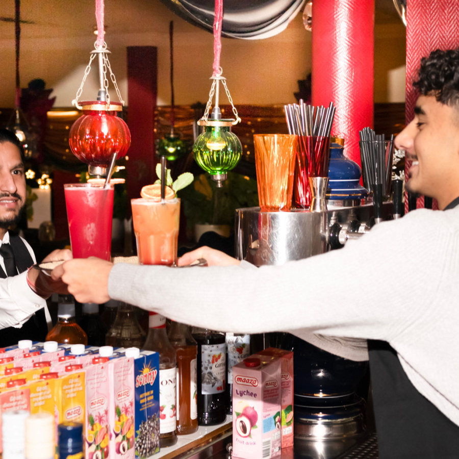 Teammitglieder an der Bar des indischen Restaurants GURU servieren frisch gemixte Drinks