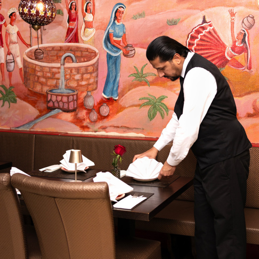 Service-Mitarbeiter des indischen Restaurants GURU richtet einen Tisch im Innenbereich